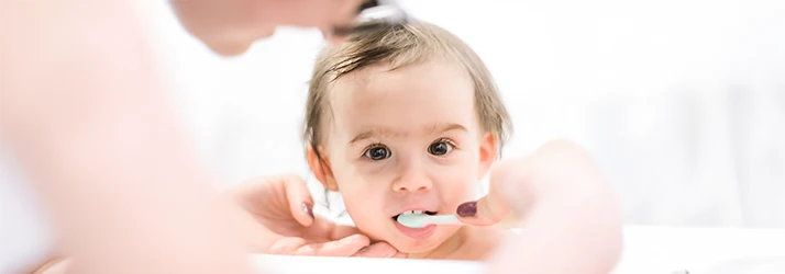 Parent gently brushing a baby's teeth, demonstrating early pediatric dental care and oral hygiene. Parent gently brushing a baby's teeth, demonstrating early pediatric dental care and oral hygiene.