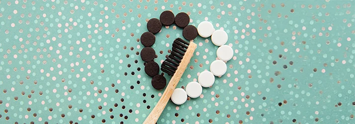 Toothbrush with charcoal toothpaste and tablets arranged in a tooth shape, symbolizing pediatric dental hygiene. Toothbrush with charcoal toothpaste and tablets arranged in a tooth shape, symbolizing pediatric dental hygiene.