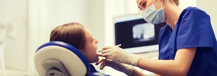 Pediatric dentist performing a dental exam on a child with dental X-rays displayed in the background. Pediatric dentist performing a dental exam on a child with dental X-rays displayed in the background.