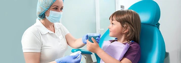 Pediatric dentist explaining fluoride treatment to a young patient, emphasizing cavity prevention for kids. Pediatric dentist explaining fluoride treatment to a young patient, emphasizing cavity prevention for kids.