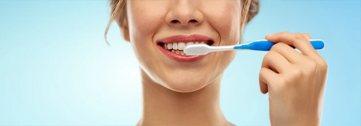 A close up of a grinning mouth as a tooth brush passes over the top teeth A close up of a grinning mouth as a tooth brush passes over the top teeth