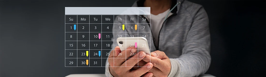 A person in a grey zip up athletic jacket holds phone, a transparent calendar lays across the foreground indicating the user scheduling an appointment A person in a grey zip up athletic jacket holds phone, a transparent calendar lays across the foreground indicating the user scheduling an appointment