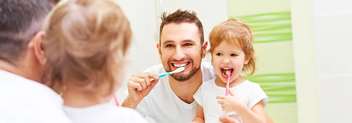 Father teaching his daughter how to brush teeth properly, promoting good pediatric dental care at home. Father teaching his daughter how to brush teeth properly, promoting good pediatric dental care at home.