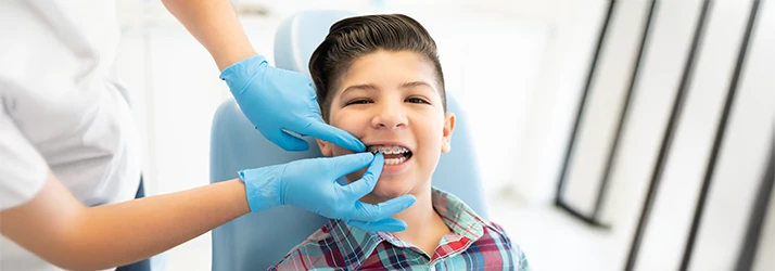 Smiling boy receiving braces adjustment at pediatric dentist office, highlighting orthodontic care for kids. Smiling boy receiving braces adjustment at pediatric dentist office, highlighting orthodontic care for kids.