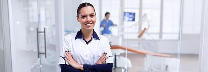 Confident orthodontist standing with arms crossed in a modern orthodontic clinic, ready to provide emergency dental care Confident orthodontist standing with arms crossed in a modern orthodontic clinic, ready to provide emergency dental care