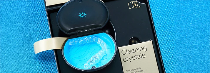 Invisalign clear aligner inside an open storage case with cleaning crystals kit, highlighting orthodontic care. Invisalign clear aligner inside an open storage case with cleaning crystals kit, highlighting orthodontic care.