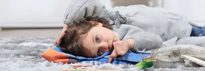 Young child lying down thumb-sucking, highlighting dental risks addressed by pediatric dentistry. Young child lying down thumb-sucking, highlighting dental risks addressed by pediatric dentistry.