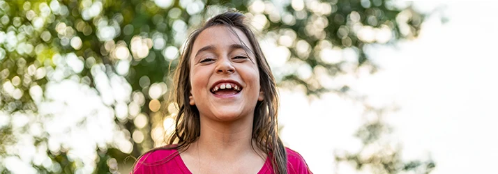 Smiling young girl showcasing healthy teeth after pediatric space maintainer care.