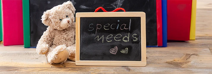 Teddy bear beside chalkboard reading 'special needs', representing pediatric special needs dentistry services.