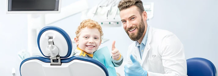 Pediatric dentist and smiling child giving thumbs-up after successful dental restoration treatment. Pediatric dentist and smiling child giving thumbs-up after successful dental restoration treatment.