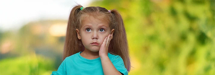 Little girl holding her cheek in pain from a toothache, representing pediatric dental care for children. Little girl holding her cheek in pain from a toothache, representing pediatric dental care for children.