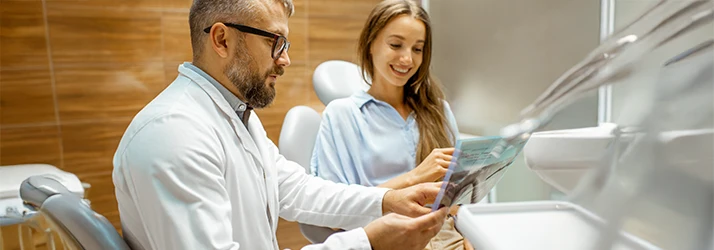 Oral surgeon reviewing jaw surgery X-rays with patient during consultation. Oral surgeon reviewing jaw surgery X-rays with patient during consultation.