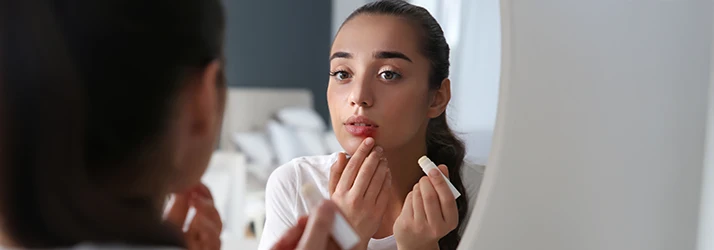 Woman examining lips in mirror, concerned about potential oral pathology conditions.
