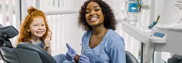 Pediatric oral surgeon and smiling child giving thumbs-up after successful oral surgery visit. Pediatric oral surgeon and smiling child giving thumbs-up after successful oral surgery visit.
