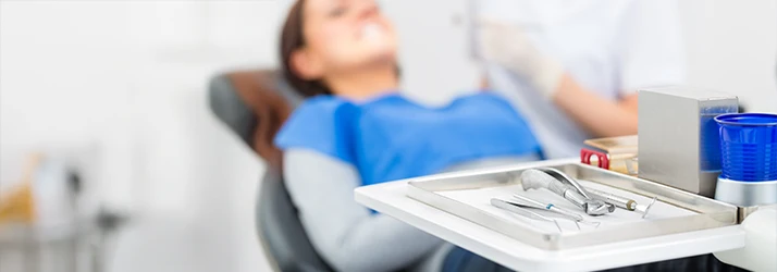Female patient receiving periodontal exam by a periodontist using a dental mirror in a modern dental office. Female patient receiving periodontal exam by a periodontist using a dental mirror in a modern dental office.
