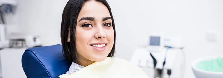 Young woman smiling comfortably in a dental chair after gum contouring treatment performed by an experienced periodontist.