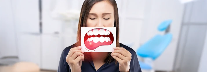 Woman holding illustration of inflamed gums, needing periodontal inflammation treatment.