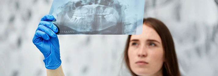 Periodontist examining dental X-ray for osseous surgery planning.