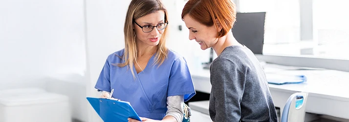 Periodontist discussing treatment options with a smiling patient, reviewing paperwork in a bright dental clinic. Periodontist discussing treatment options with a smiling patient, reviewing paperwork in a bright dental clinic.
