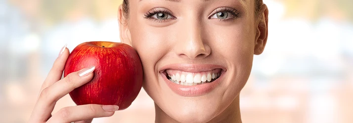Smiling woman holding apple showing healthy gums after periodontal treatment. Smiling woman holding apple showing healthy gums after periodontal treatment.