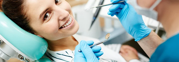 Smiling patient receiving professional teeth cleaning from periodontist. Smiling patient receiving professional teeth cleaning from periodontist.