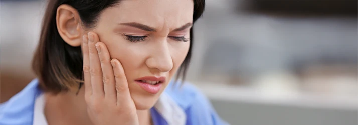Woman experiencing toothache and gum pain needing periodontist.