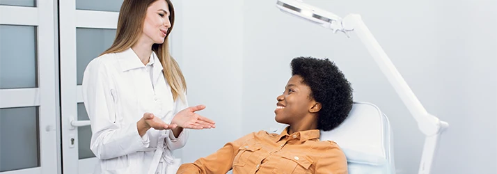 Periodontist explaining periodontal disease and gum treatment options to a smiling patient. Periodontist explaining periodontal disease and gum treatment options to a smiling patient.