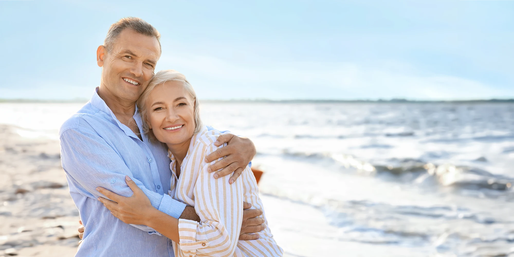 Middle-Aged-Couple-Embracing-on-a-Beach-at-Sunset.webp