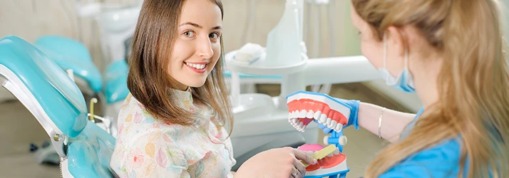 Lady-Being-Shown-How-To-Brush-Properly-On-A-Set-Of-Plastic-Teeth.webp