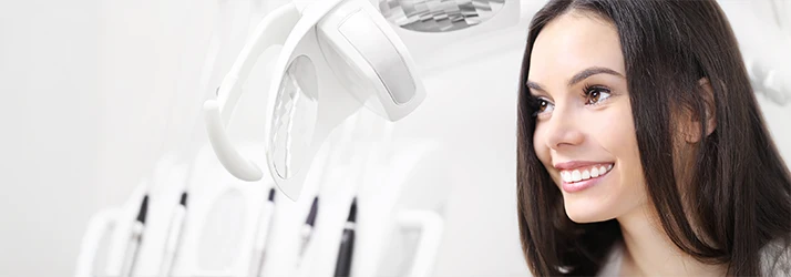 Woman-At-The-Dentists-Office-With-Blurred-Equipment-Behind-Her.webp